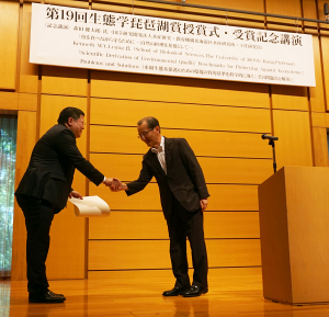 梁美儀教授（左）從滋賀縣副縣長西嶋栄治先生（右）的手中接過生態學琵琶湖獎獎狀